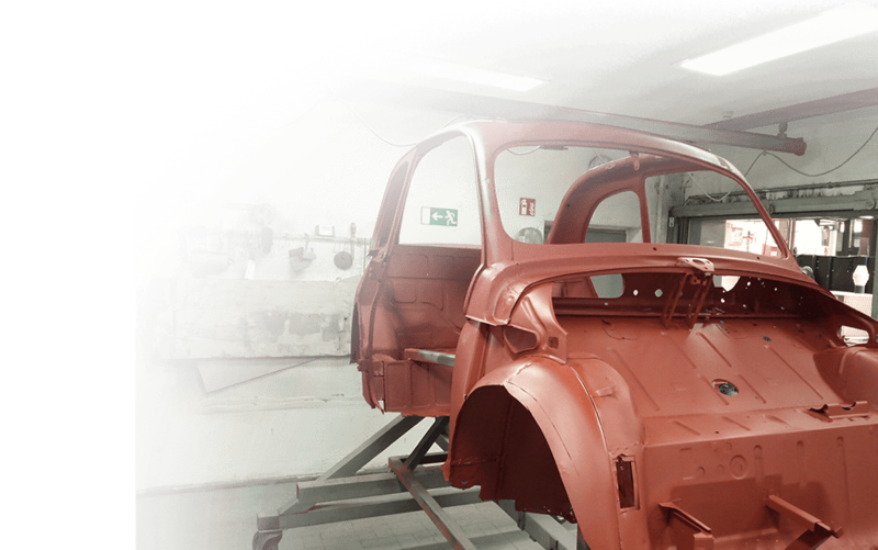 Eine rot lackierte Karosserie ohne Türen und Fenster auf einem Werkstattständer